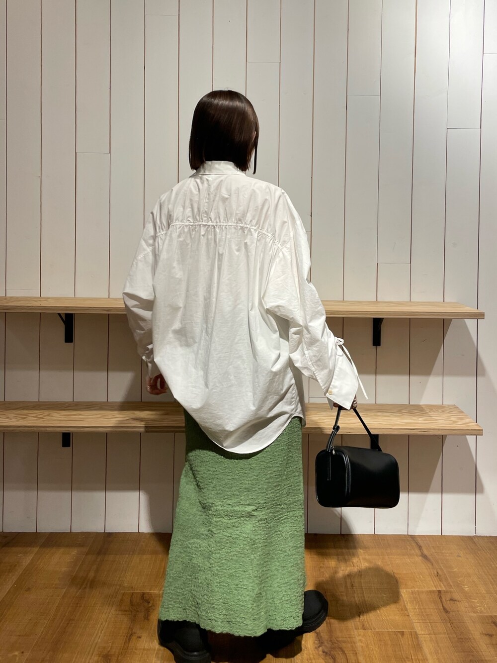 ブラック系のハンドバッグ、ブラック系のブーツ、ホワイト系のシャツ/ブラウスを着用したレディースの冬コーディネートの3枚目の写真