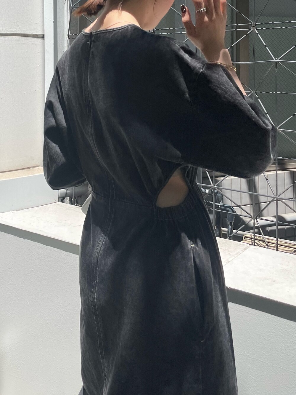 ホワイト系のハンドバッグ、ブラック系のブーツ、ブラック系のワンピースを着用したレディースの夏コーディネートの5枚目の写真