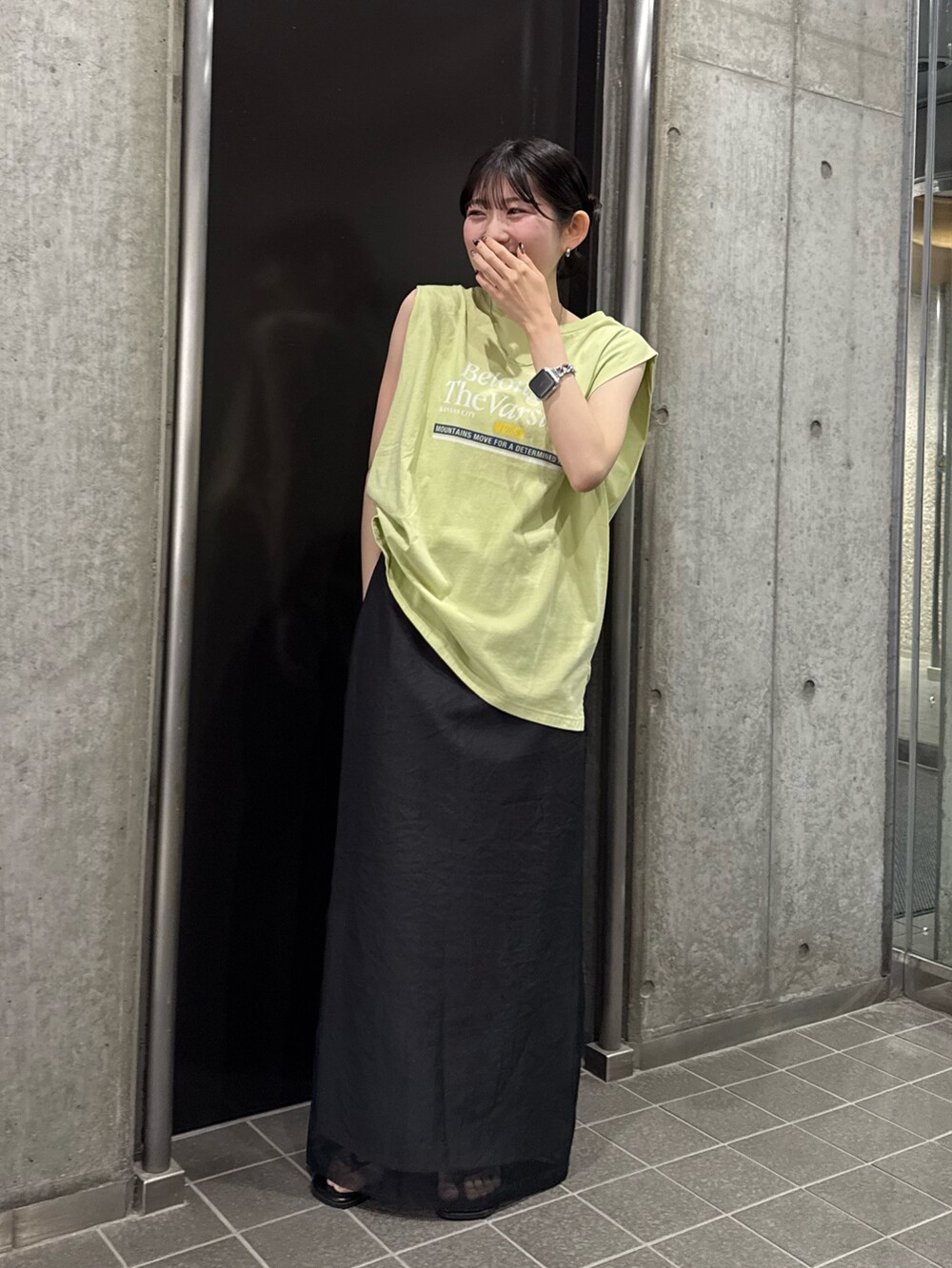 グレー系のスカート、グリーン系のタンクトップ、ブラック系のサンダルを着用したレディースの夏コーディネートの6枚目の写真