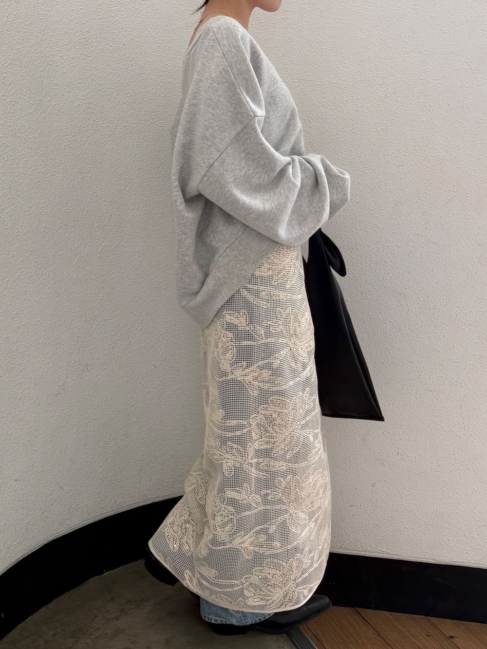 ブラック系のハンドバッグ、ブラック系のブーツ、ブルー系のデニムパンツを着用したレディースの春コーディネートの5枚目の写真