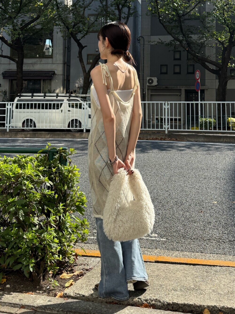 ブラウン系のブーツ、ホワイト系のハンドバッグ、ブルー系のデニムパンツを着用したレディースの秋コーディネートの5枚目の写真