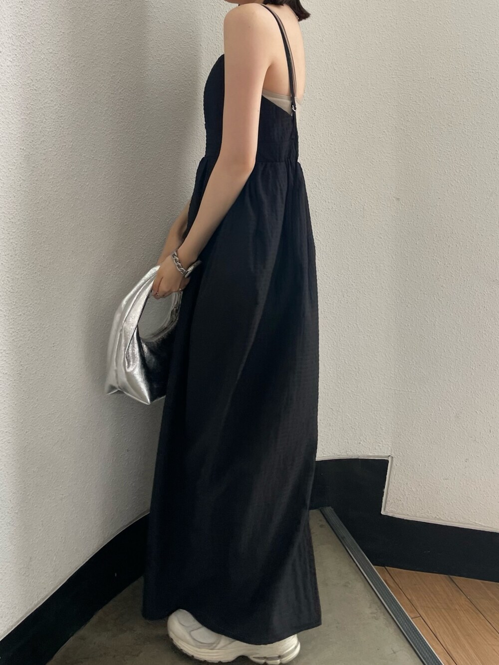 グレー系のキャミソール、シルバー系のハンドバッグ、ブラック系のワンピースを着用したレディースの春コーディネートの4枚目の写真