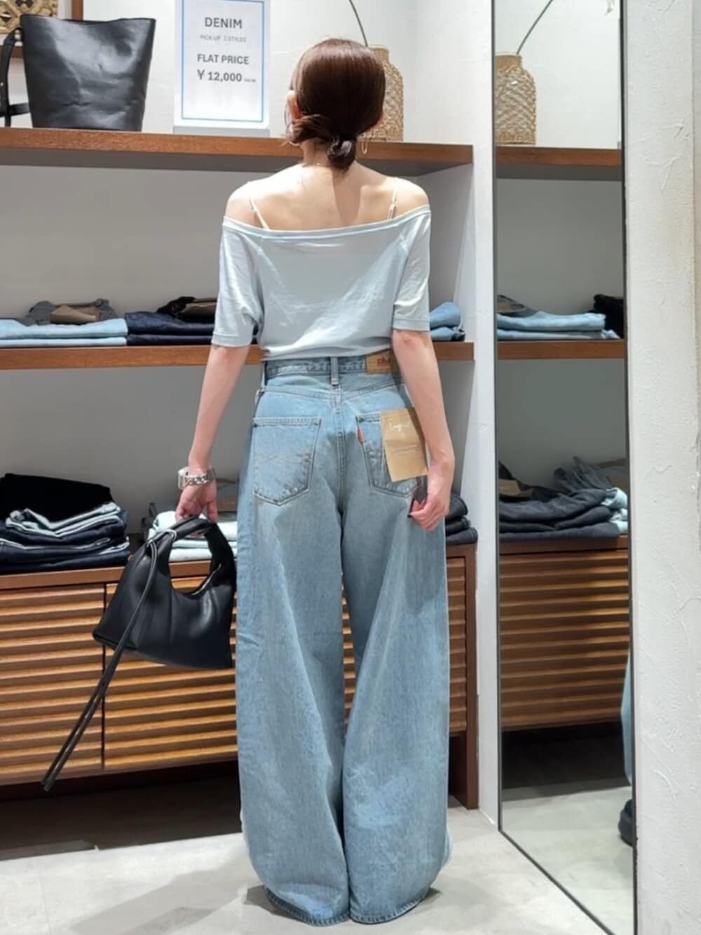 ブラック系のハンドバッグ、ブルー系のTシャツ/カットソー、ブルー系のデニムパンツを着用したレディースの春コーディネートの3枚目の写真
