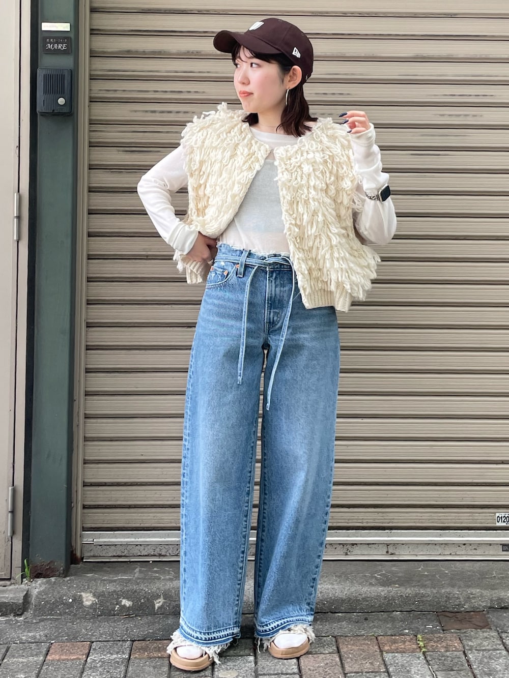 ホワイト系のサンダル、ブルー系のデニムパンツ、ホワイト系のベストを着用したレディースの夏コーディネートの8枚目の写真