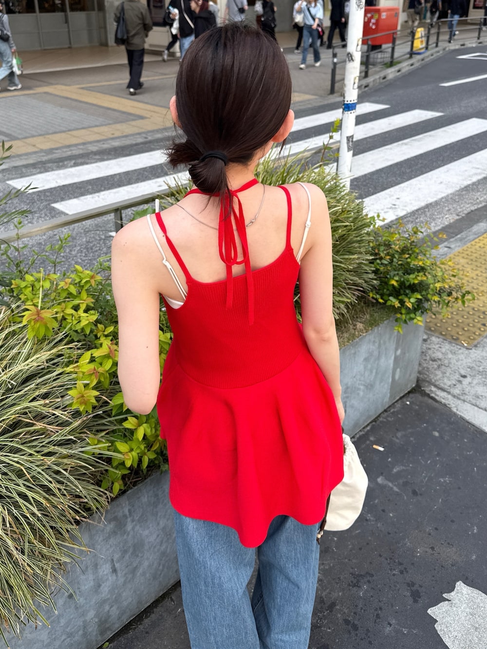 レッド系のキャミソール、ブルー系のデニムパンツ、ブラック系のブーツを着用したレディースの春コーディネートの2枚目の写真