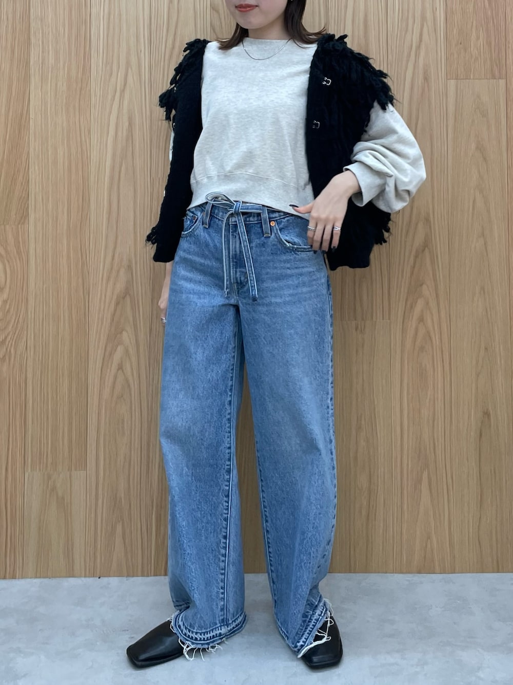 ブルー系のデニムパンツ、ブラック系のブーツ、グレー系のスウェットを着用したレディースの秋コーディネートの3枚目の写真