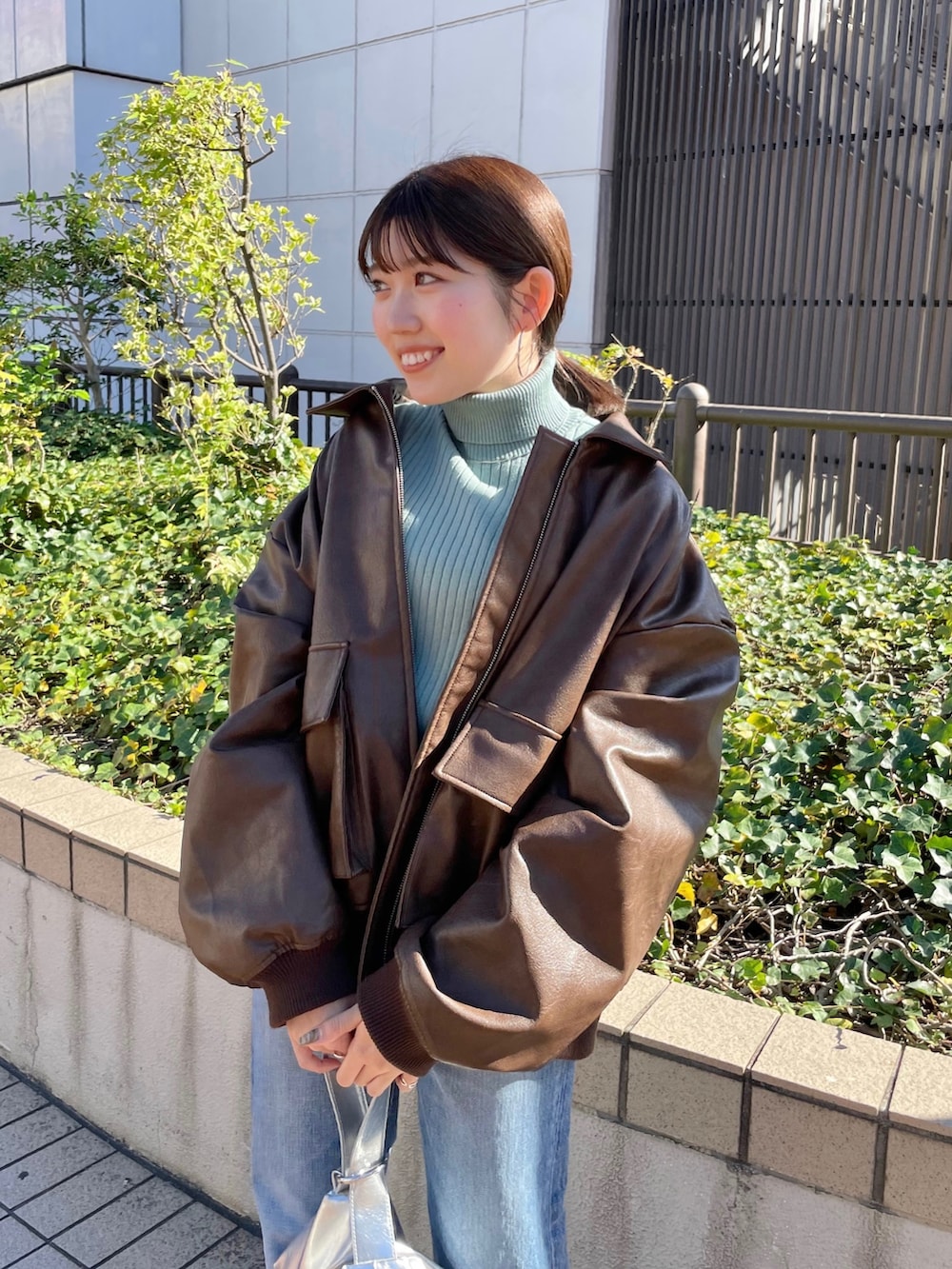 ブラウン系のブルゾン、ブラック系のパンプス、ブルー系のデニムパンツを着用したレディースの秋コーディネートの2枚目の写真