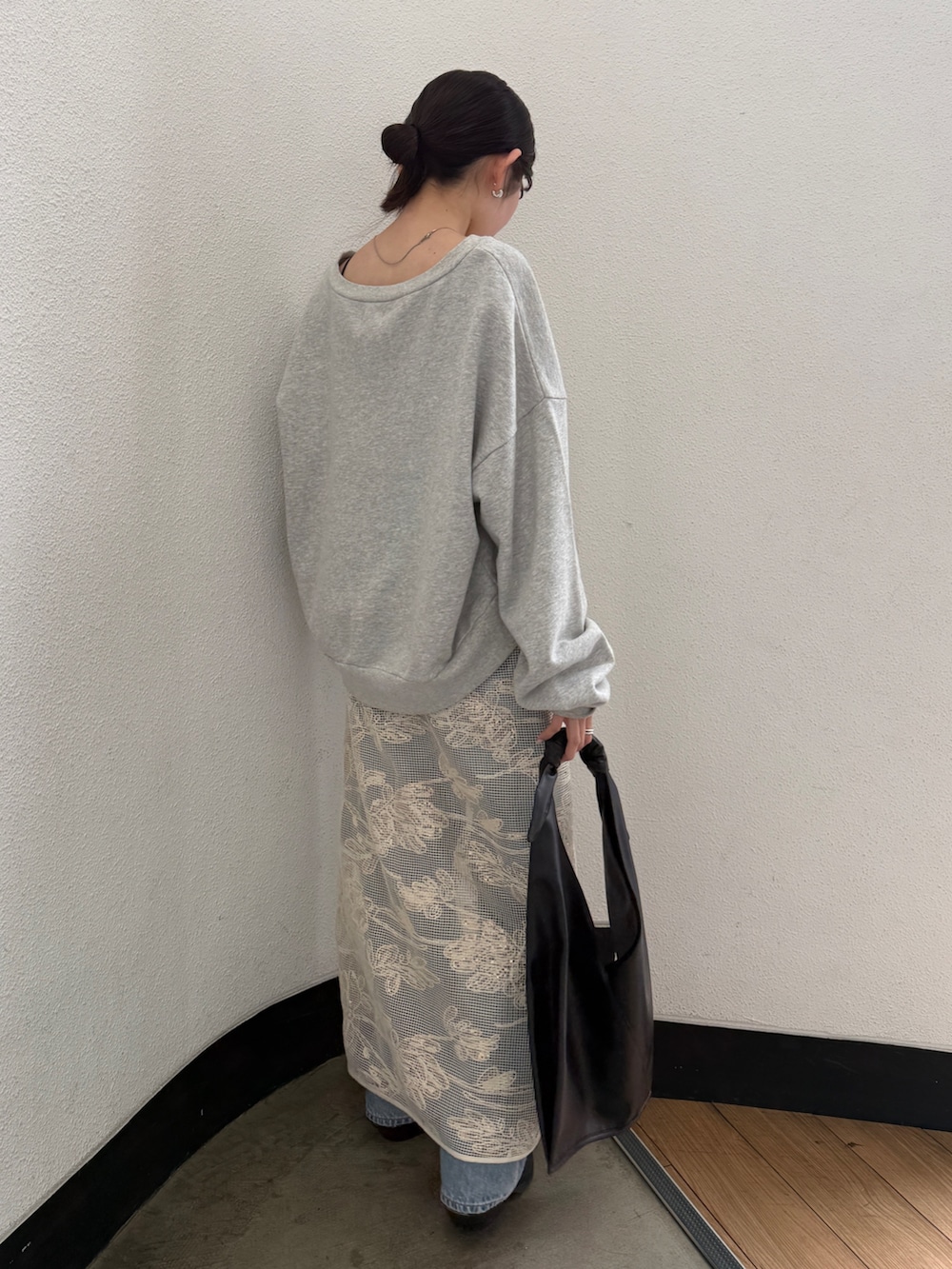 ブラック系のハンドバッグ、ブラック系のブーツ、ブルー系のデニムパンツを着用したレディースの春コーディネートの7枚目の写真