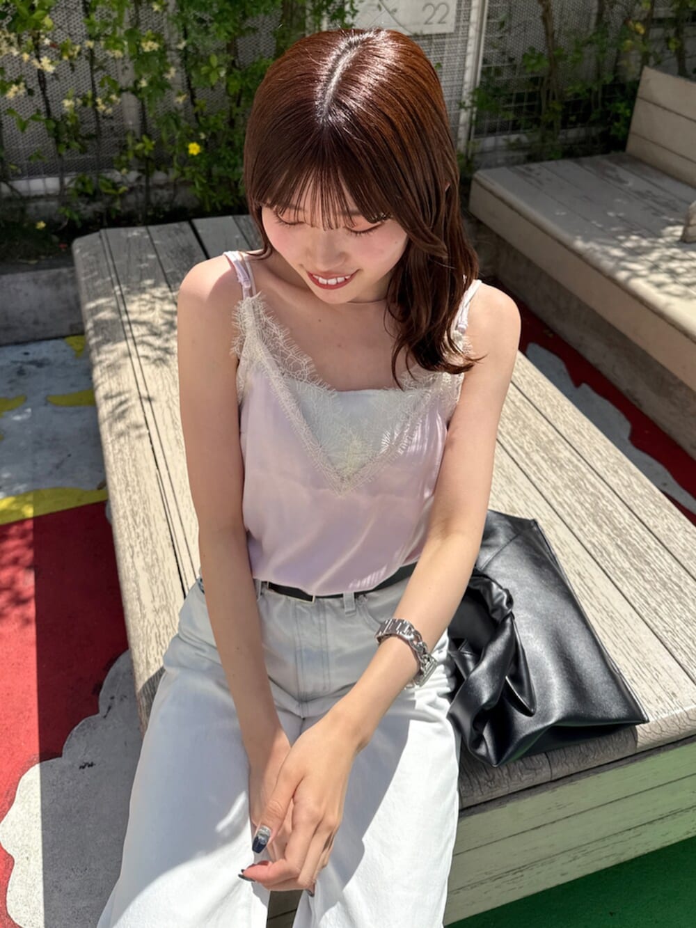 ブラック系のハンドバッグ、ホワイト系のデニムパンツ、ピンク系のキャミソールを着用したレディースの春コーディネートの4枚目の写真