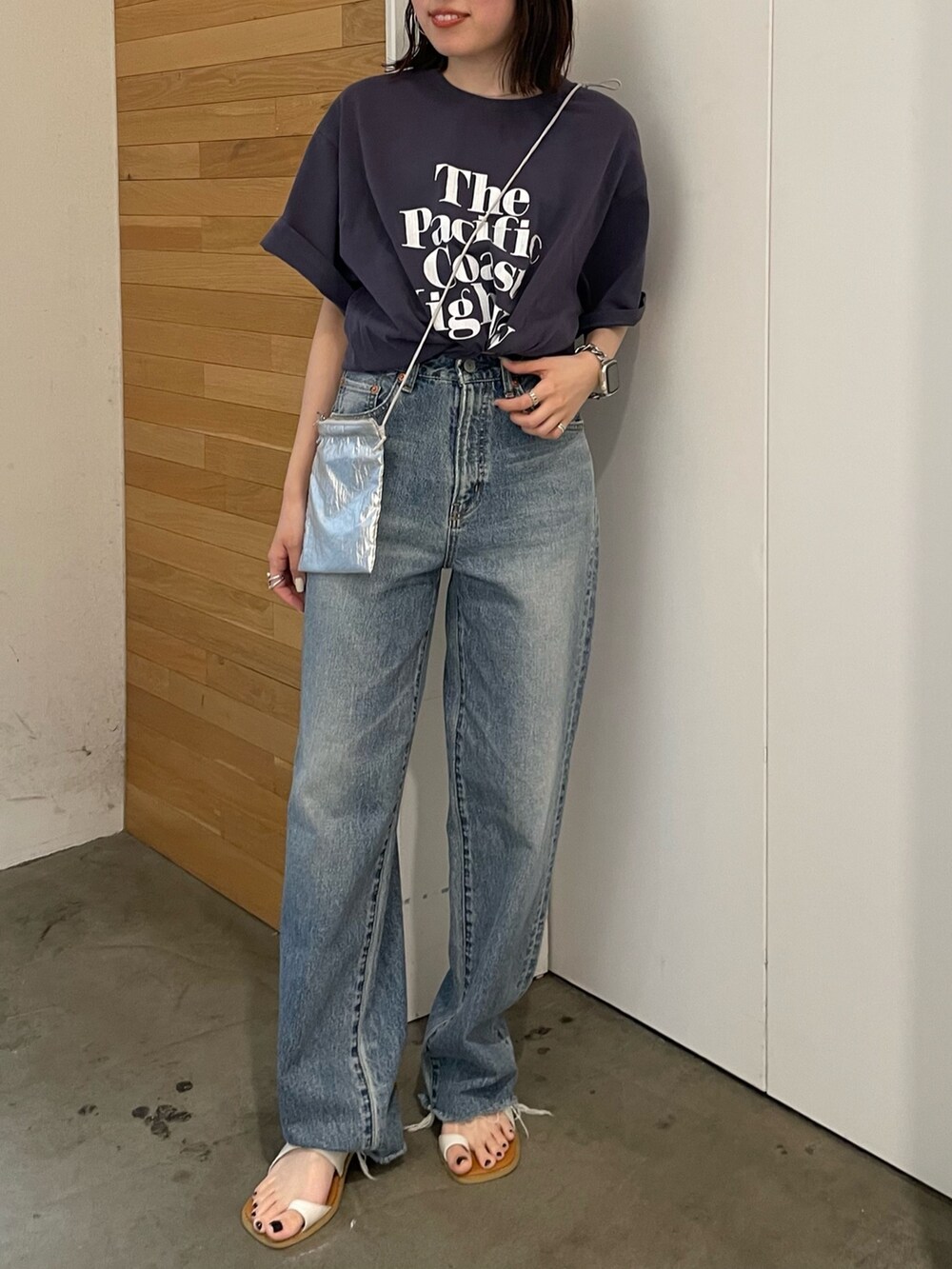 ホワイト系のサンダル、ブルー系のデニムパンツ、シルバー系のショルダーバッグを着用したレディースの春コーディネートの2枚目の写真