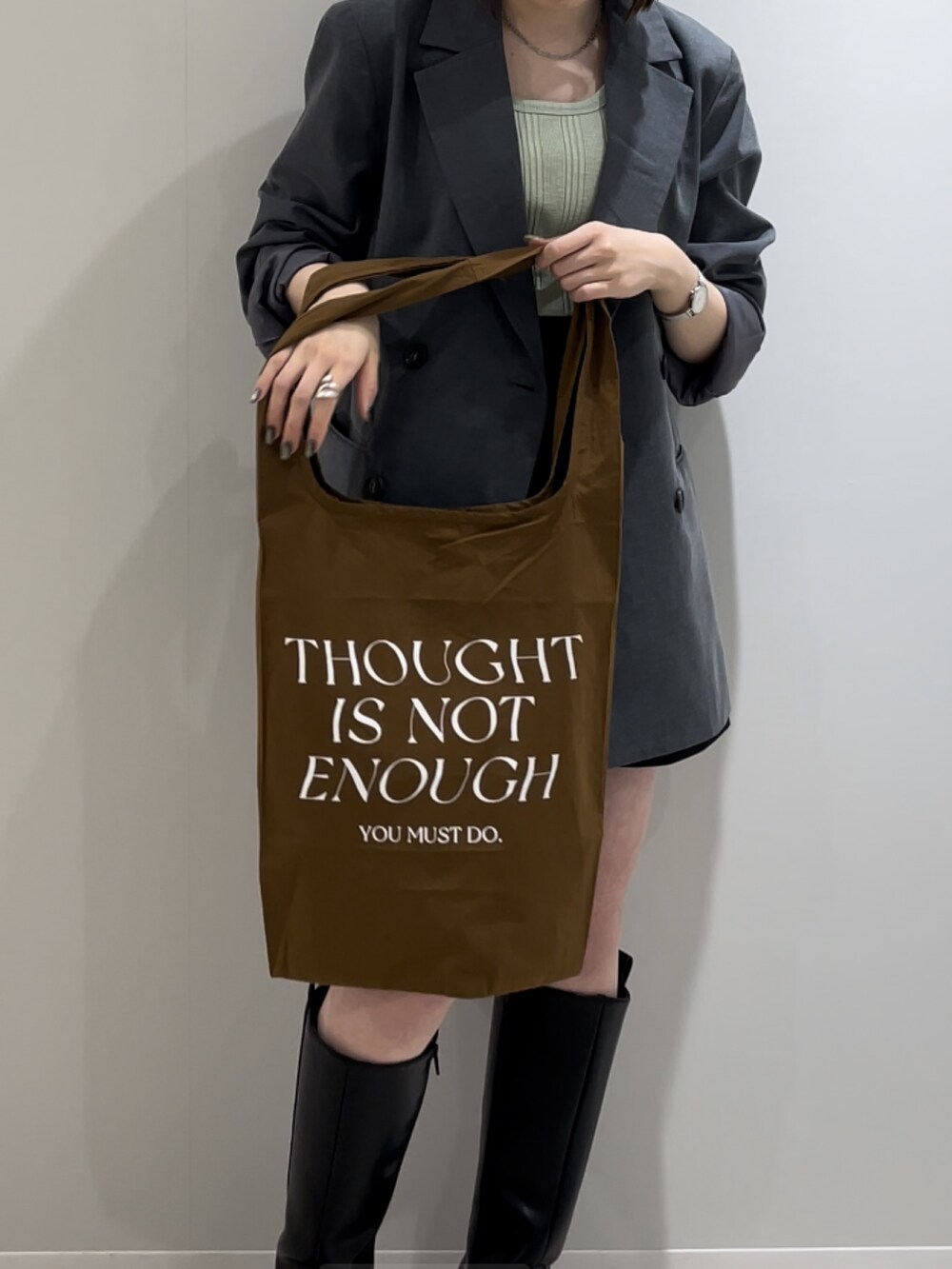 グレー系のテーラードジャケット、グリーン系のタンクトップ、ブラウン系のエコバッグ/サブバッグを着用したレディースの冬コーディネートの3枚目の写真