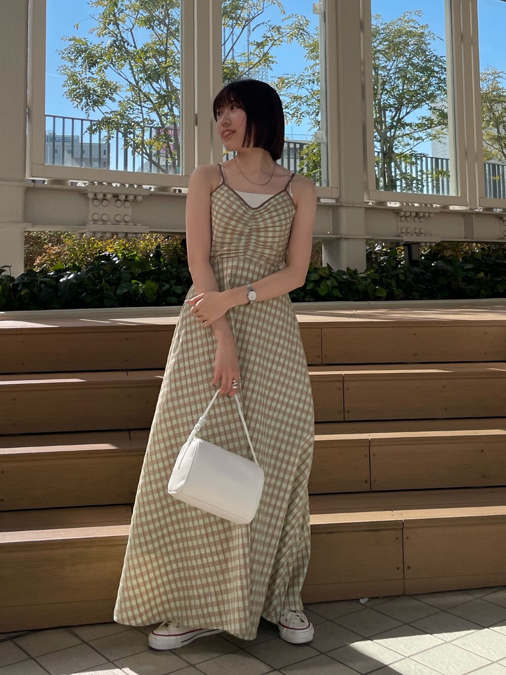 ホワイト系のハンドバッグ、グリーン系のワンピース、ブルー系のデニムジャケットを着用したレディースの冬コーディネートの2枚目の写真