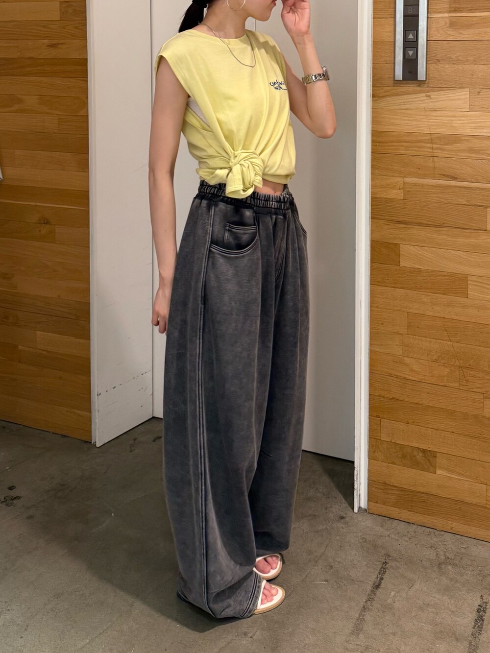 グレー系のスウェットパンツ、イエロー系のタンクトップ、ホワイト系のサンダルを着用したレディースの夏コーディネートの3枚目の写真