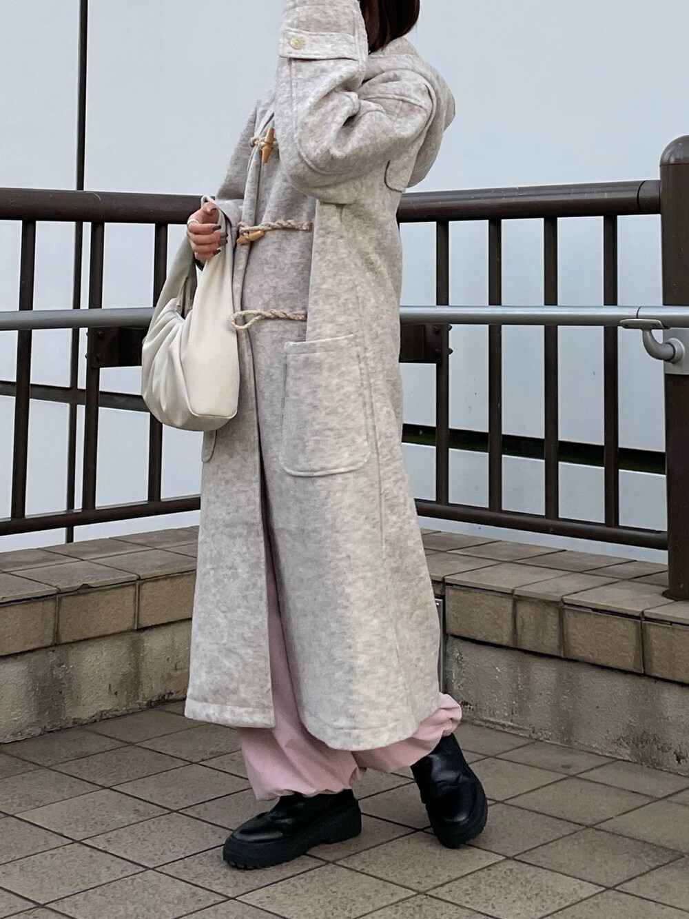 ピンク系のカーゴパンツ、ホワイト系のハンドバッグ、ホワイト系のダッフルコートを着用したレディースの冬コーディネートの4枚目の写真
