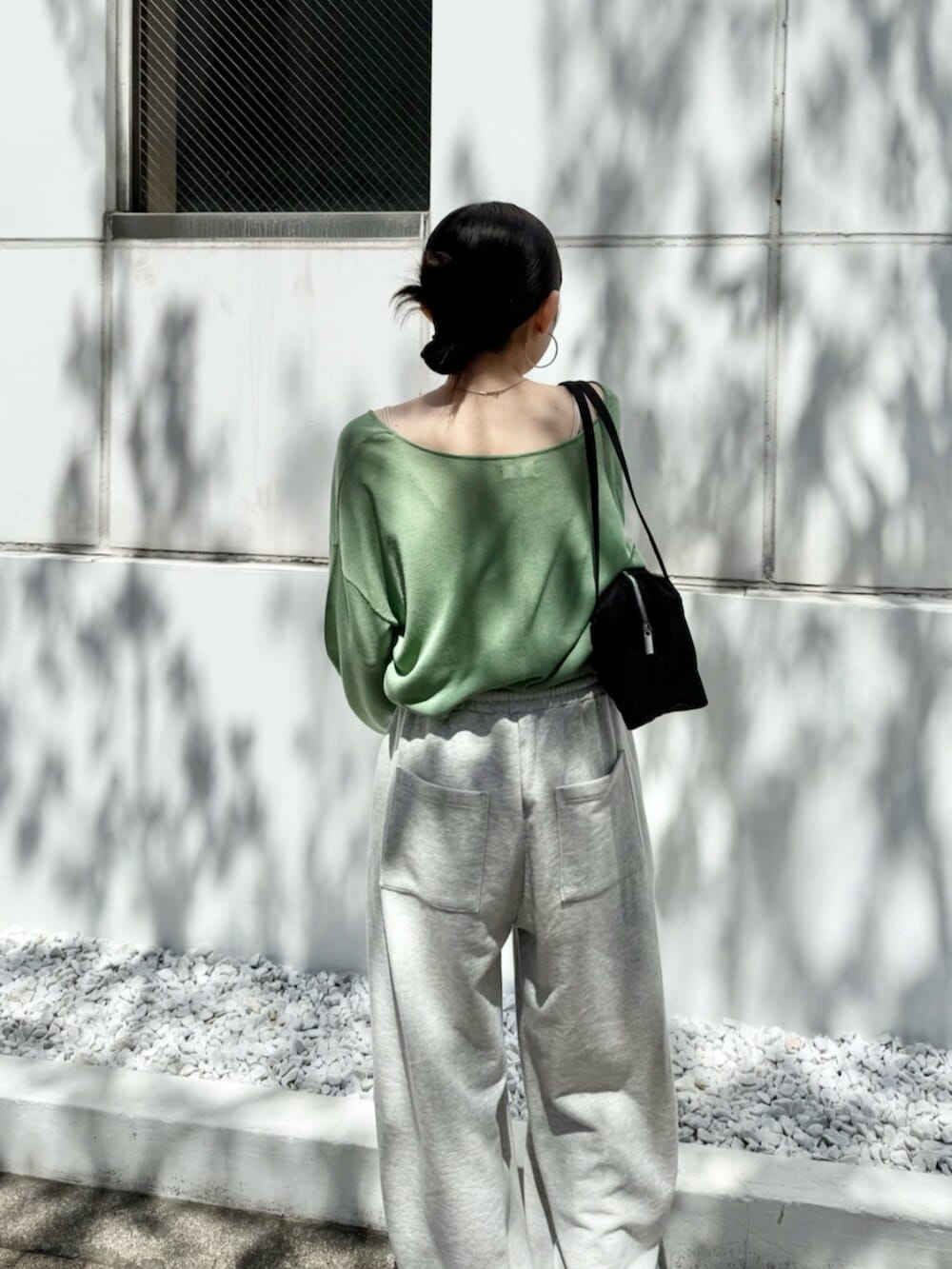グレー系のスウェットパンツ、ブラック系のハンドバッグ、グリーン系のニット/セーターを着用したレディースの春コーディネートの8枚目の写真