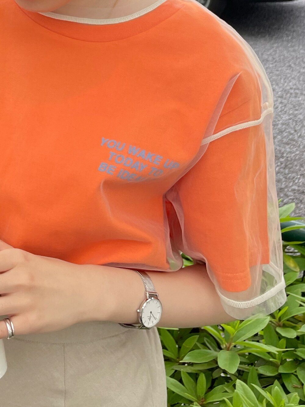 ホワイト系のサンダル、オレンジ系のTシャツ/カットソー、ベージュ系のスカートを着用したレディースの春コーディネートの6枚目の写真