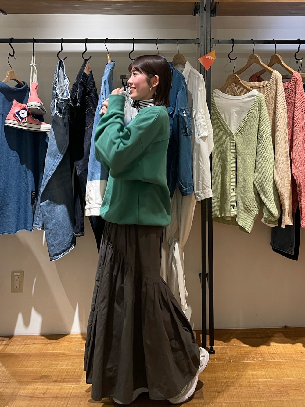 グレー系のスカート、グリーン系のスウェット、ホワイト系のニット/セーターを着用したレディースの冬コーディネートの3枚目の写真