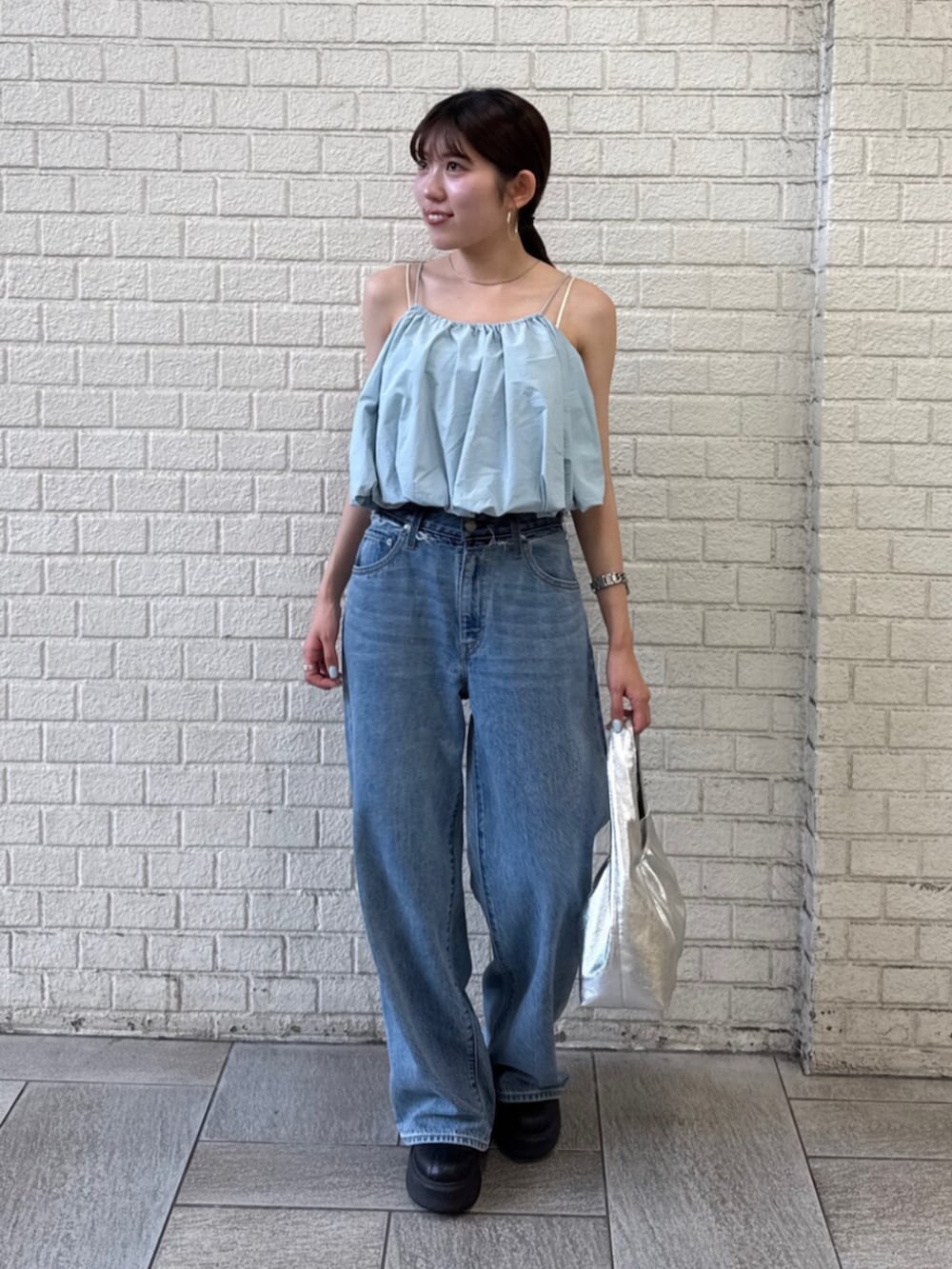 シルバー系のハンドバッグ、ブルー系のデニムパンツ、ブルー系のキャミソールを着用したレディースの夏コーディネートの7枚目の写真