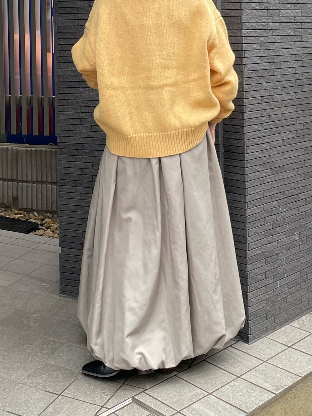 ブラック系のブーツ、イエロー系のニット/セーター、グレー系のスカートを着用したレディースの冬コーディネートの7枚目の写真