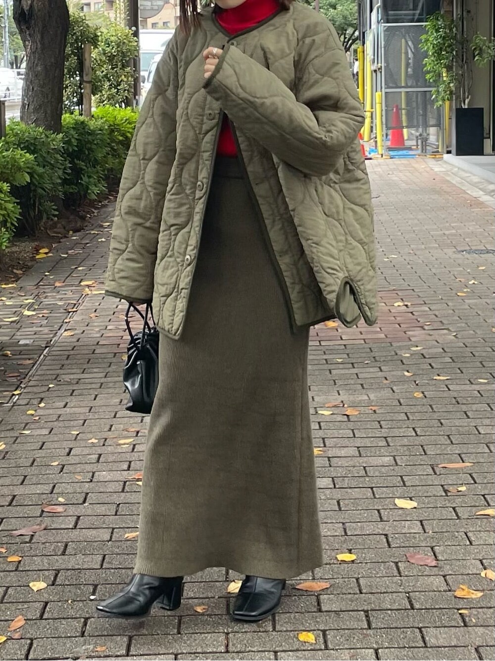 ブラック系のブーツ、グリーン系のブルゾン、レッド系のニット/セーターを着用したレディースの秋コーディネートの3枚目の写真