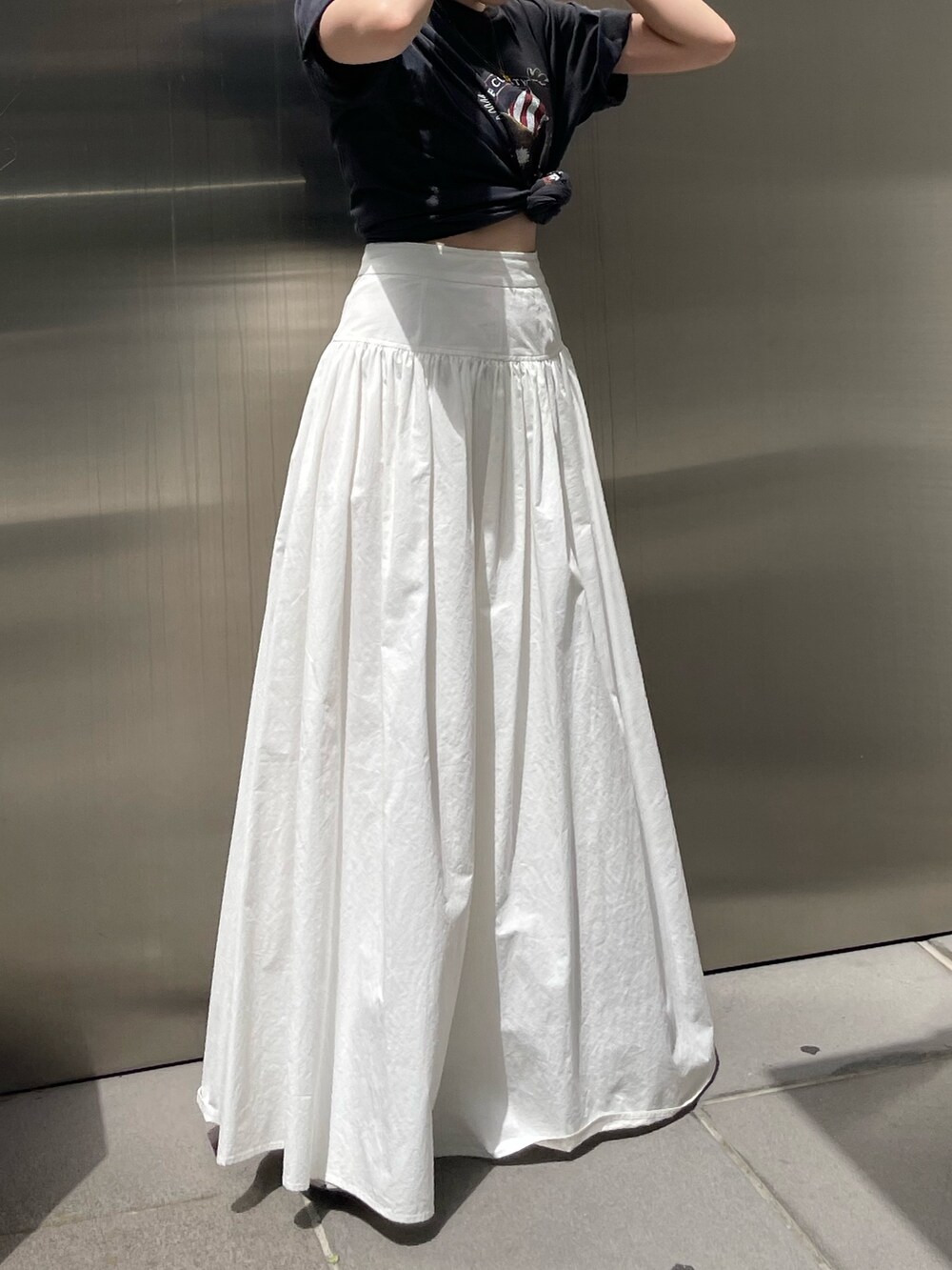 ホワイト系のスカート、グレー系のTシャツ/カットソー、ゴールド系のネックレスを着用したレディースの春コーディネートの4枚目の写真