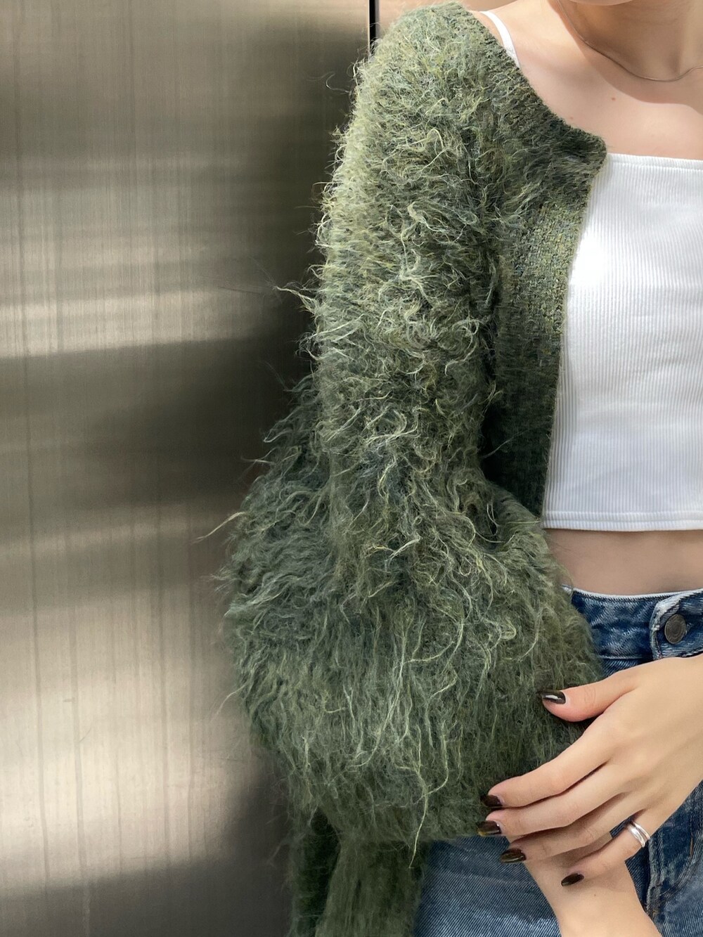 グリーン系のカーディガン/ボレロ、ベージュ系のブーツ、ブルー系のデニムパンツを着用したレディースの秋コーディネートの7枚目の写真