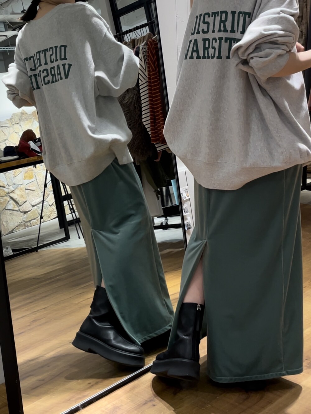 グリーン系のワンピース、ブラック系のブーツ、グレー系のスウェットを着用したレディースの秋コーディネートの4枚目の写真