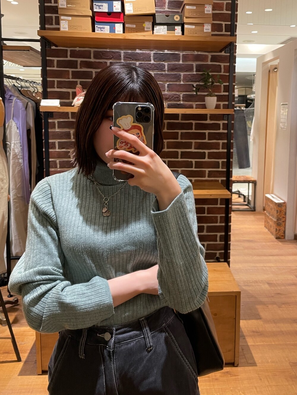 グリーン系のニット/セーター、ブラック系のショルダーバッグ、ブラック系のデニムパンツを着用したレディースの冬コーディネートの4枚目の写真