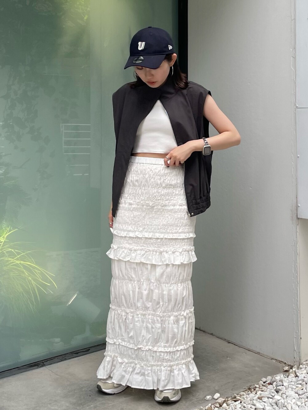 グレー系のベスト、ホワイト系のスカート、ブルー系のキャップを着用したレディースの夏コーディネートの3枚目の写真
