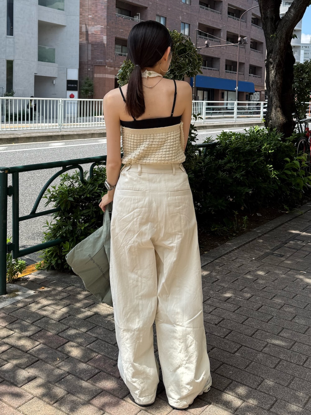 ホワイト系のチノパンツ、グリーン系のトートバッグ、ホワイト系のタンクトップを着用したレディースの夏コーディネートの2枚目の写真