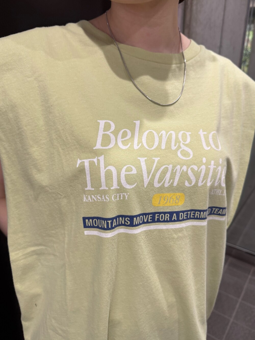 グレー系のスカート、グリーン系のタンクトップ、ブラック系のサンダルを着用したレディースの夏コーディネートの7枚目の写真