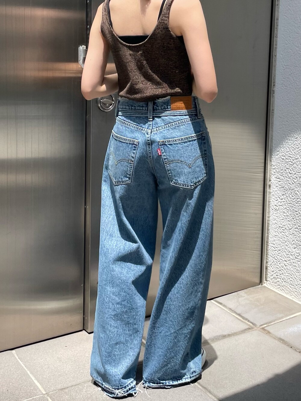 ブラウン系のベスト、ブルー系のデニムパンツ、ブルー系のキャップを着用したレディースの夏コーディネートの8枚目の写真