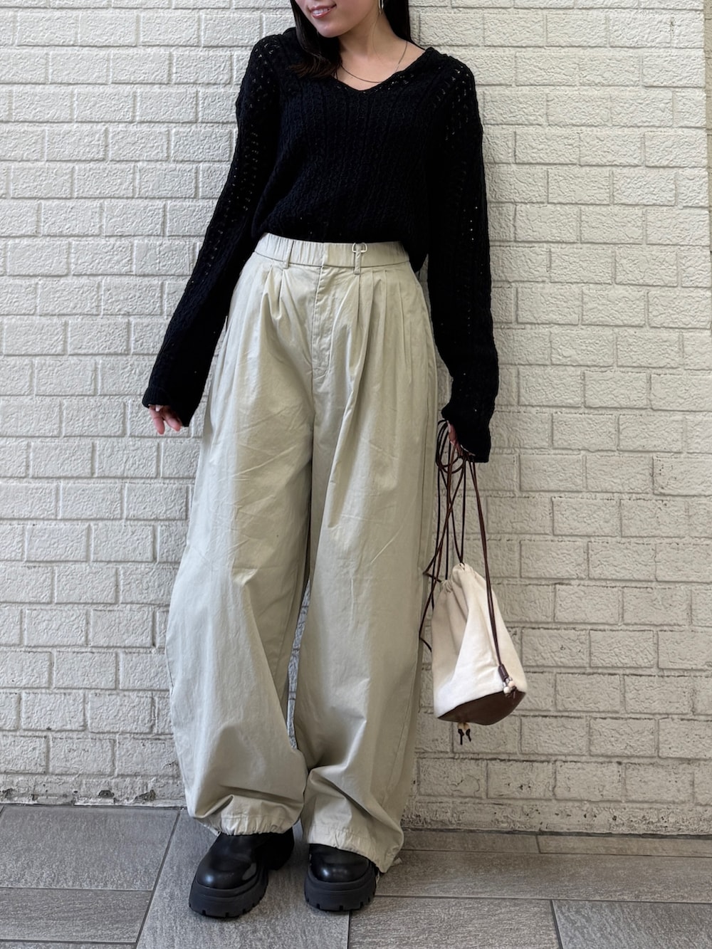 ベージュ系のその他パンツ、ホワイト系のショルダーバッグ、ブラック系のニット/セーターを着用したレディースの春コーディネートの5枚目の写真