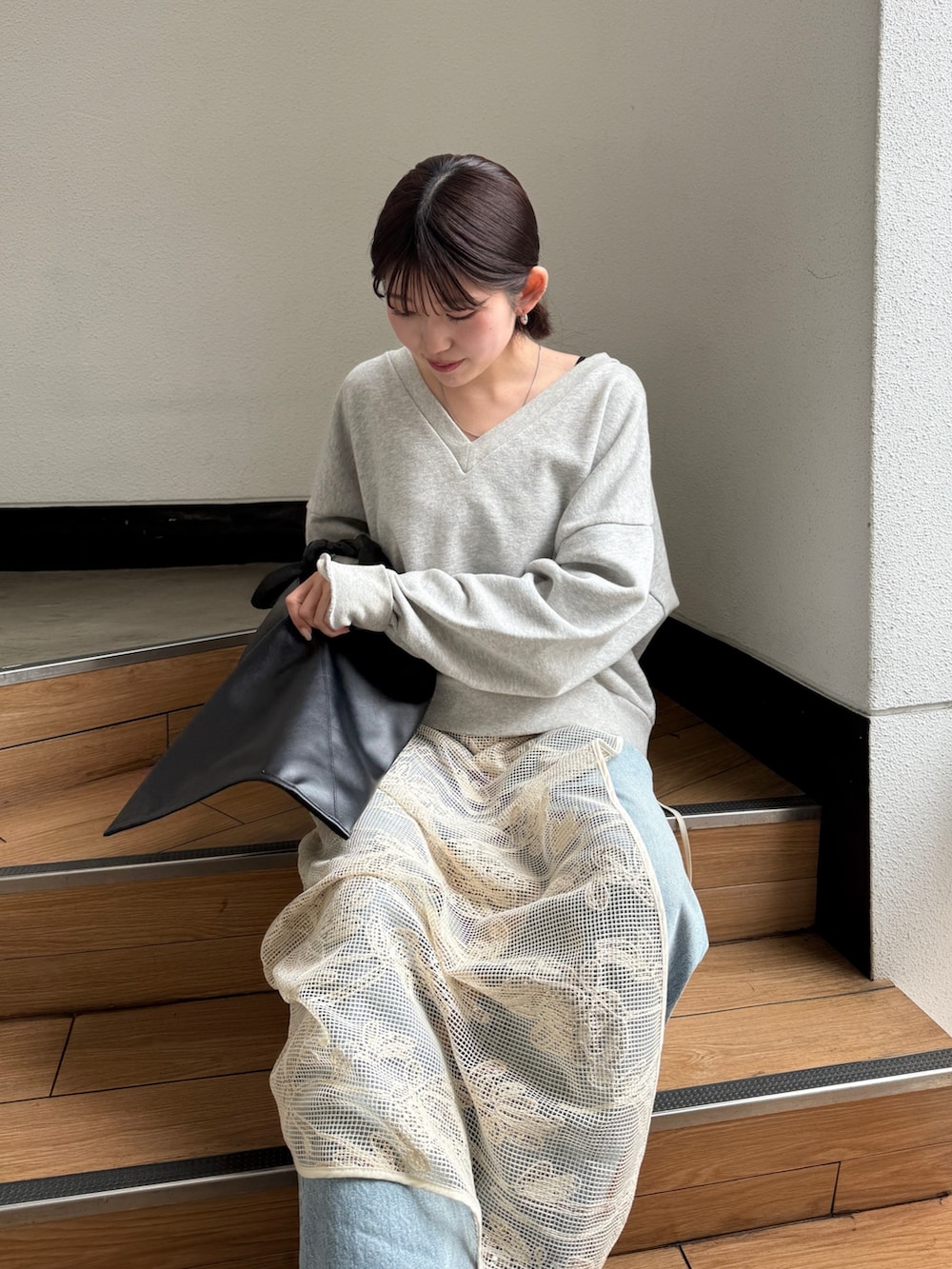 ブラック系のハンドバッグ、ブラック系のブーツ、ブルー系のデニムパンツを着用したレディースの春コーディネートの4枚目の写真