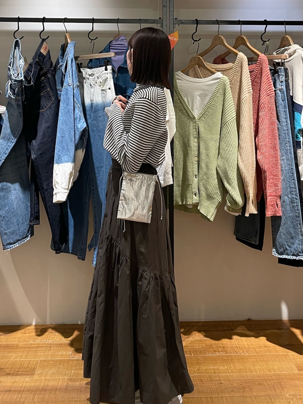 グレー系のスカート、ホワイト系のニット/セーター、シルバー系のショルダーバッグを着用したレディースの冬コーディネートの6枚目の写真