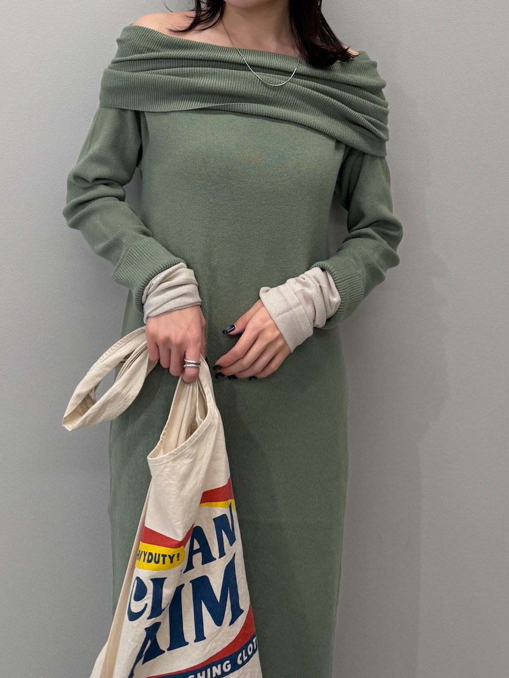 ホワイト系のトートバッグ、ブラック系のブーツ、グリーン系のワンピースを着用したレディースの冬コーディネートの5枚目の写真