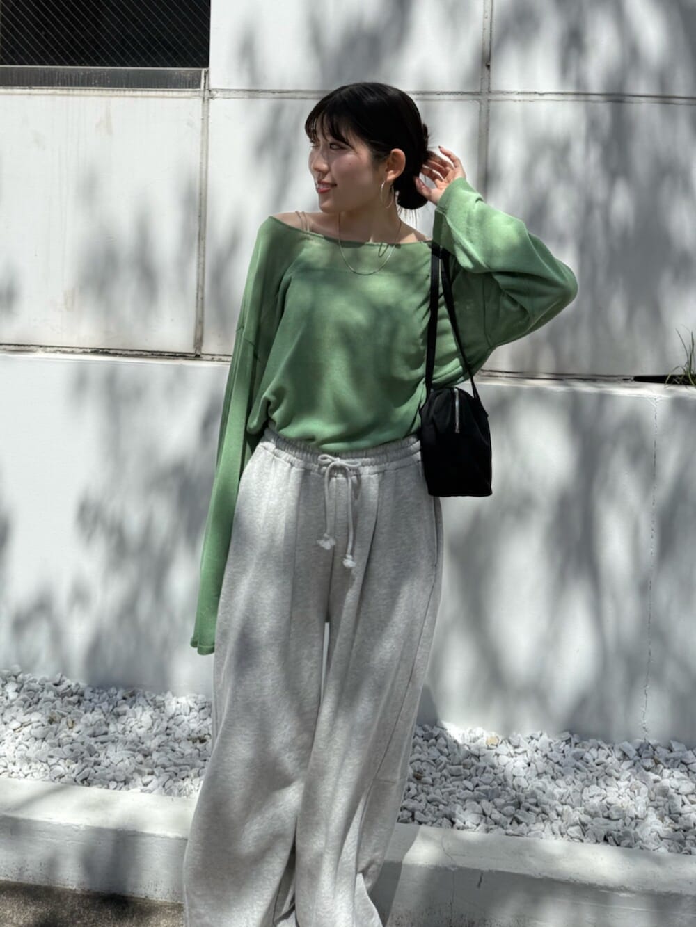 グレー系のスウェットパンツ、ブラック系のハンドバッグ、グリーン系のニット/セーターを着用したレディースの春コーディネートの7枚目の写真