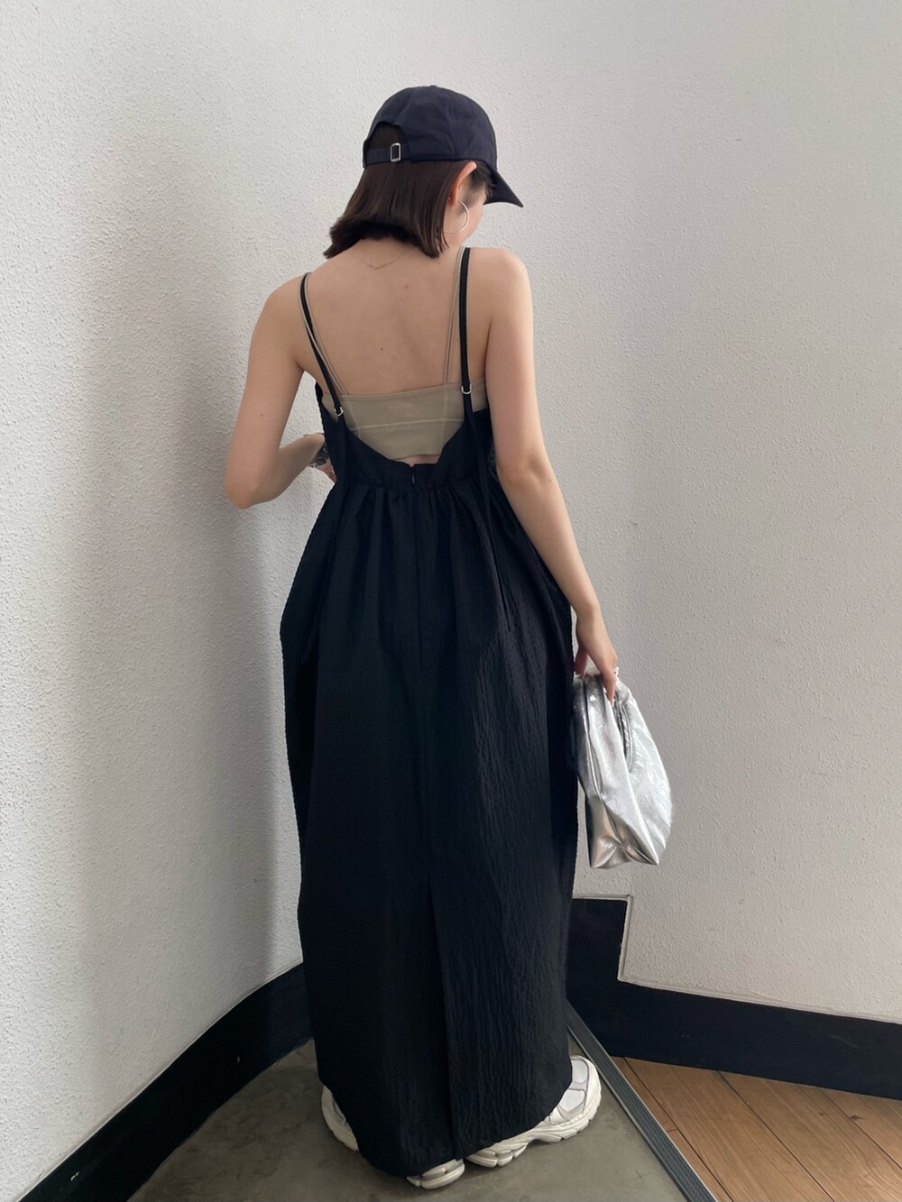 グレー系のキャミソール、シルバー系のハンドバッグ、ブラック系のワンピースを着用したレディースの春コーディネートの3枚目の写真