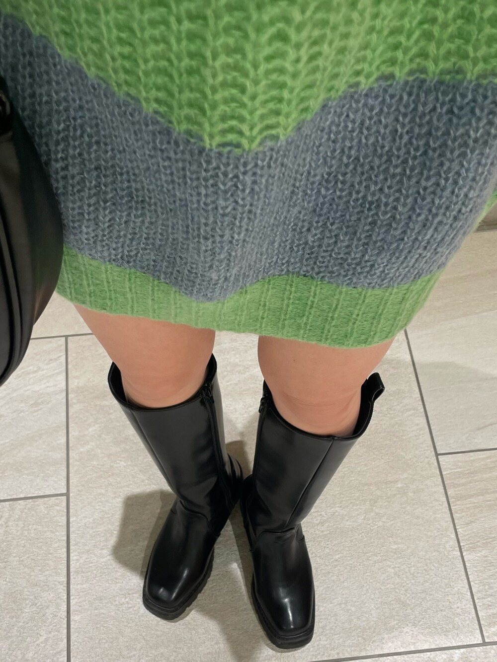 グリーン系のニット/セーター、ホワイト系のTシャツ/カットソー、グレー系のマフラーを着用したレディースの冬コーディネートの6枚目の写真