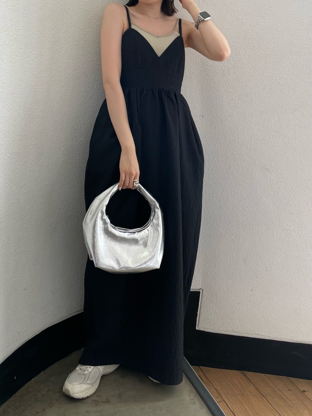 グレー系のキャミソール、シルバー系のハンドバッグ、ブラック系のワンピースを着用したレディースの春コーディネートの2枚目の写真