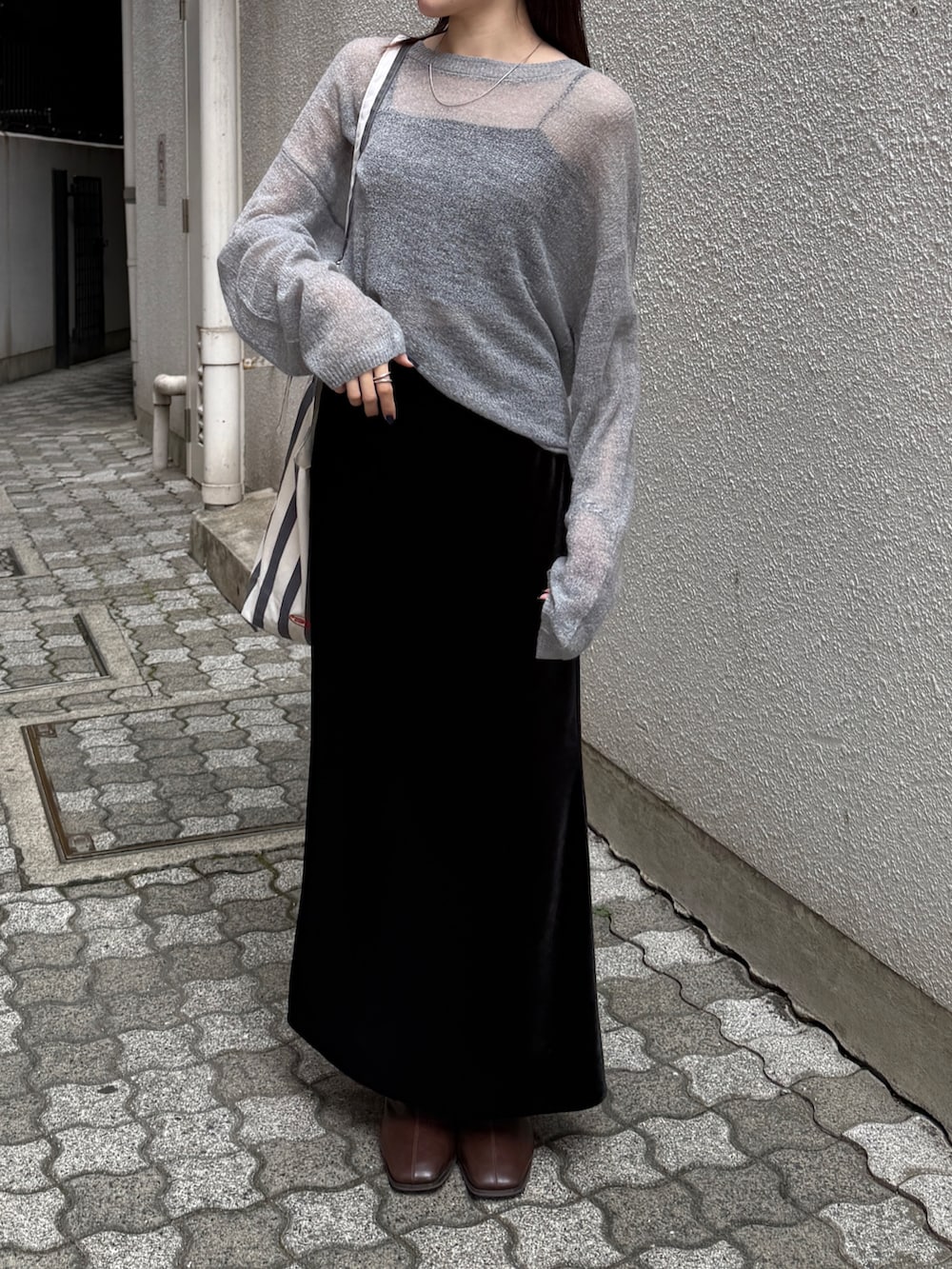 ブラック系のスカート、ブラウン系のブーツ、グレー系のニット/セーターを着用したレディースの秋コーディネートの2枚目の写真