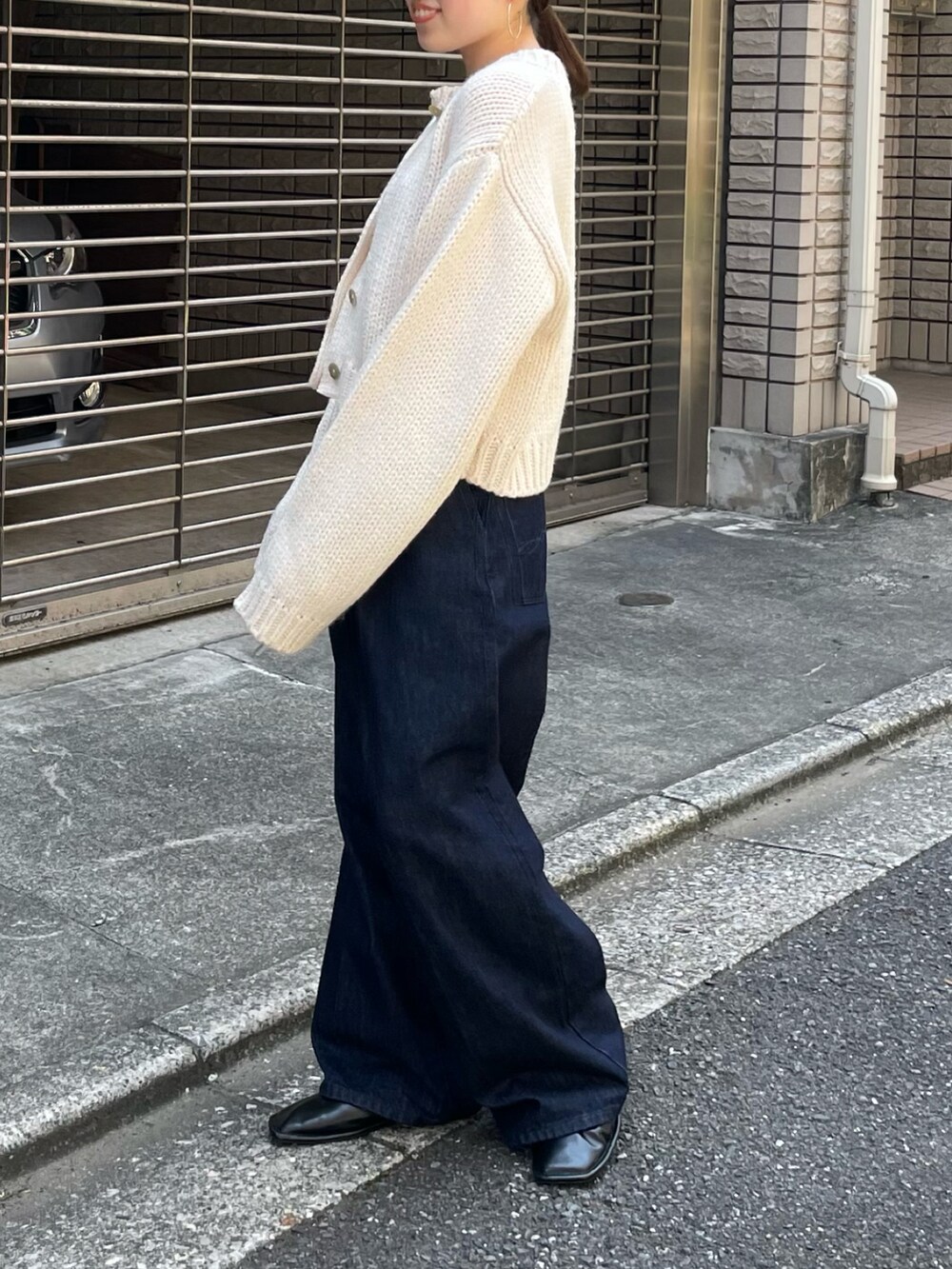 ブラック系のローファー、ブルー系のデニムパンツ、ホワイト系のカーディガン/ボレロを着用したレディースの秋コーディネートの3枚目の写真