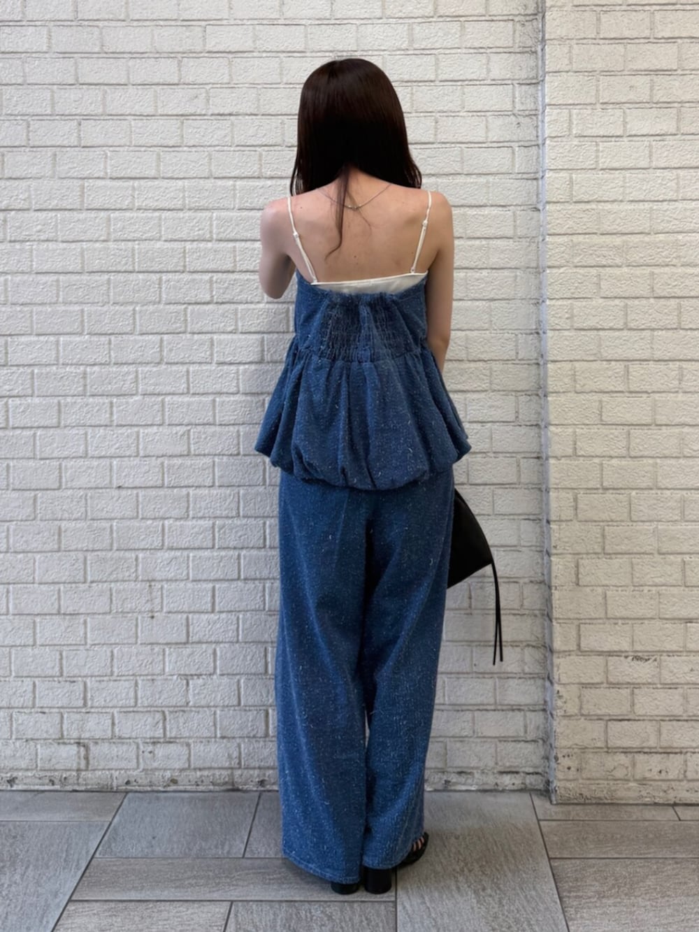 ブルー系のチューブトップ、ブルー系のデニムパンツ、ブラック系のハンドバッグを着用したレディースの夏コーディネートの3枚目の写真