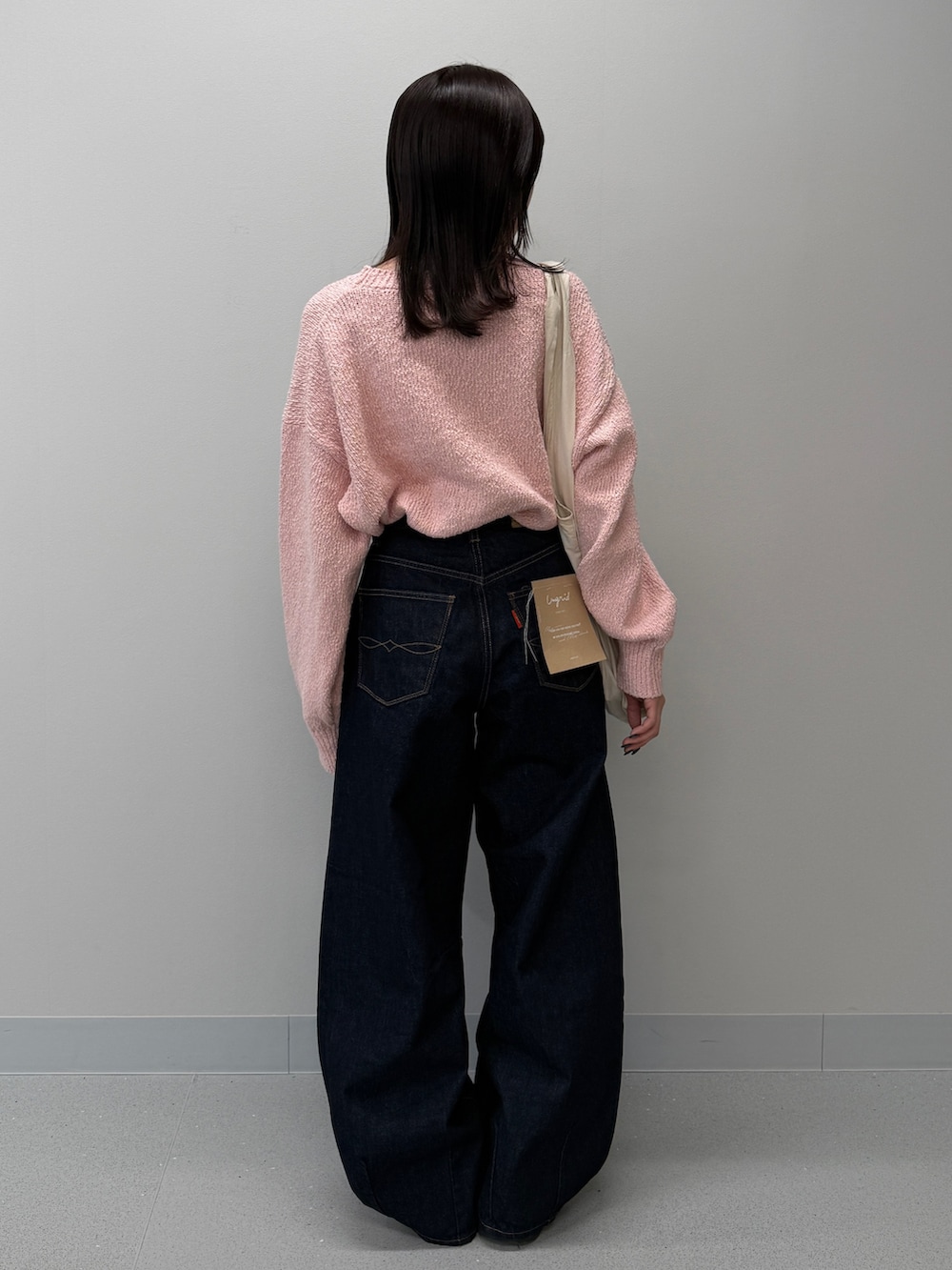 ブルー系のデニムパンツ、ブラック系のブーツ、ピンク系のニット/セーターを着用したレディースの冬コーディネートの4枚目の写真