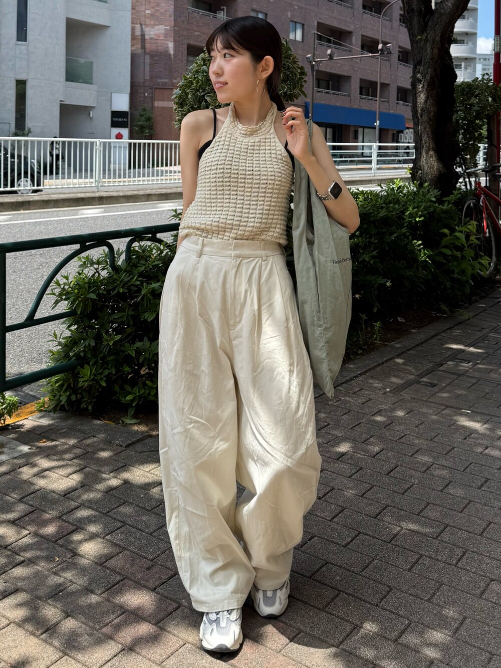 ホワイト系のチノパンツ、グリーン系のトートバッグ、ホワイト系のタンクトップを着用したレディースの夏コーディネートの3枚目の写真