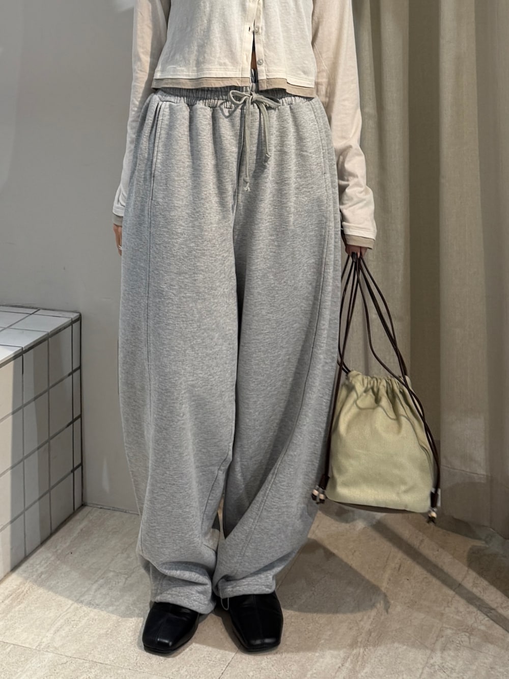 グレー系のスウェットパンツ、ブラック系のサンダル、ホワイト系のカーディガン/ボレロを着用したレディースの冬コーディネートの4枚目の写真