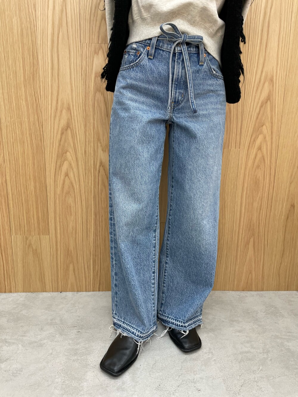 ブルー系のデニムパンツ、ブラック系のブーツ、グレー系のスウェットを着用したレディースの秋コーディネートの6枚目の写真