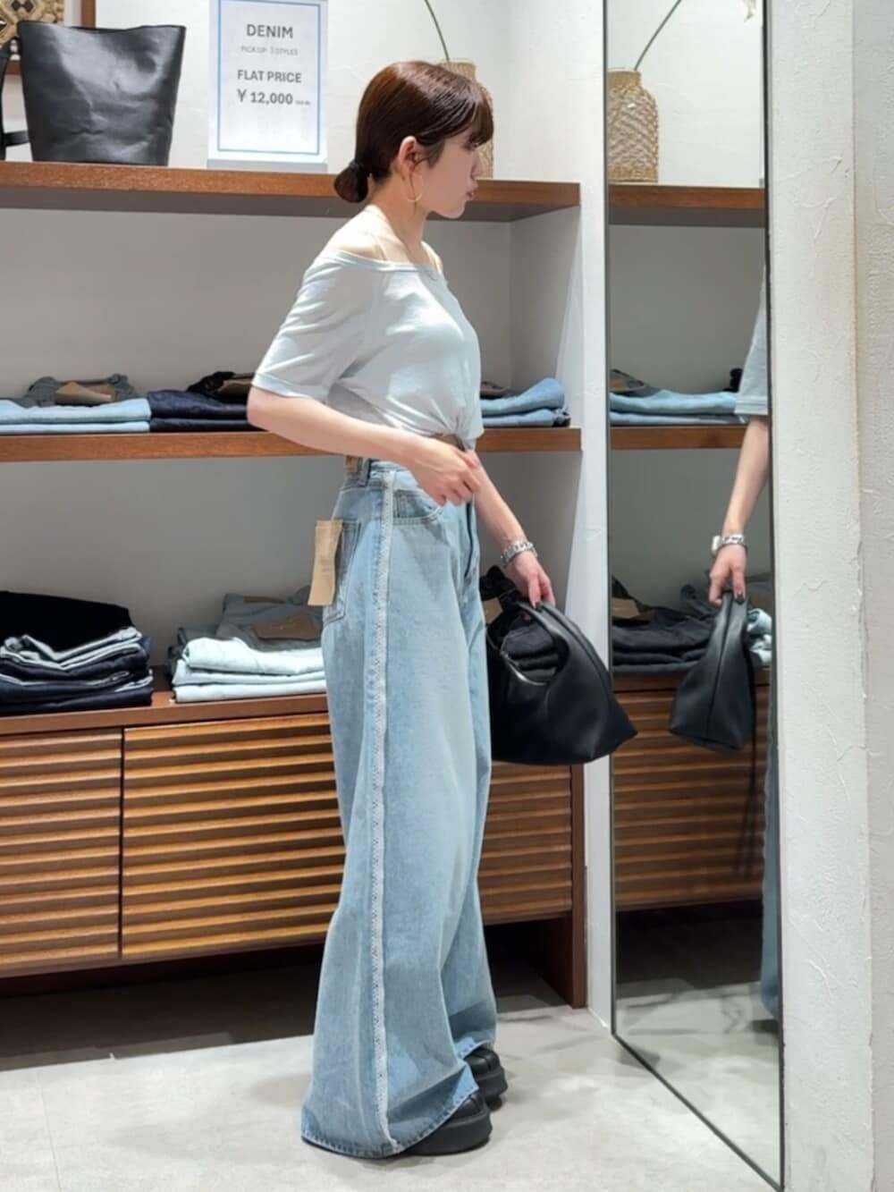 ブラック系のハンドバッグ、ブルー系のTシャツ/カットソー、ブルー系のデニムパンツを着用したレディースの春コーディネートの4枚目の写真