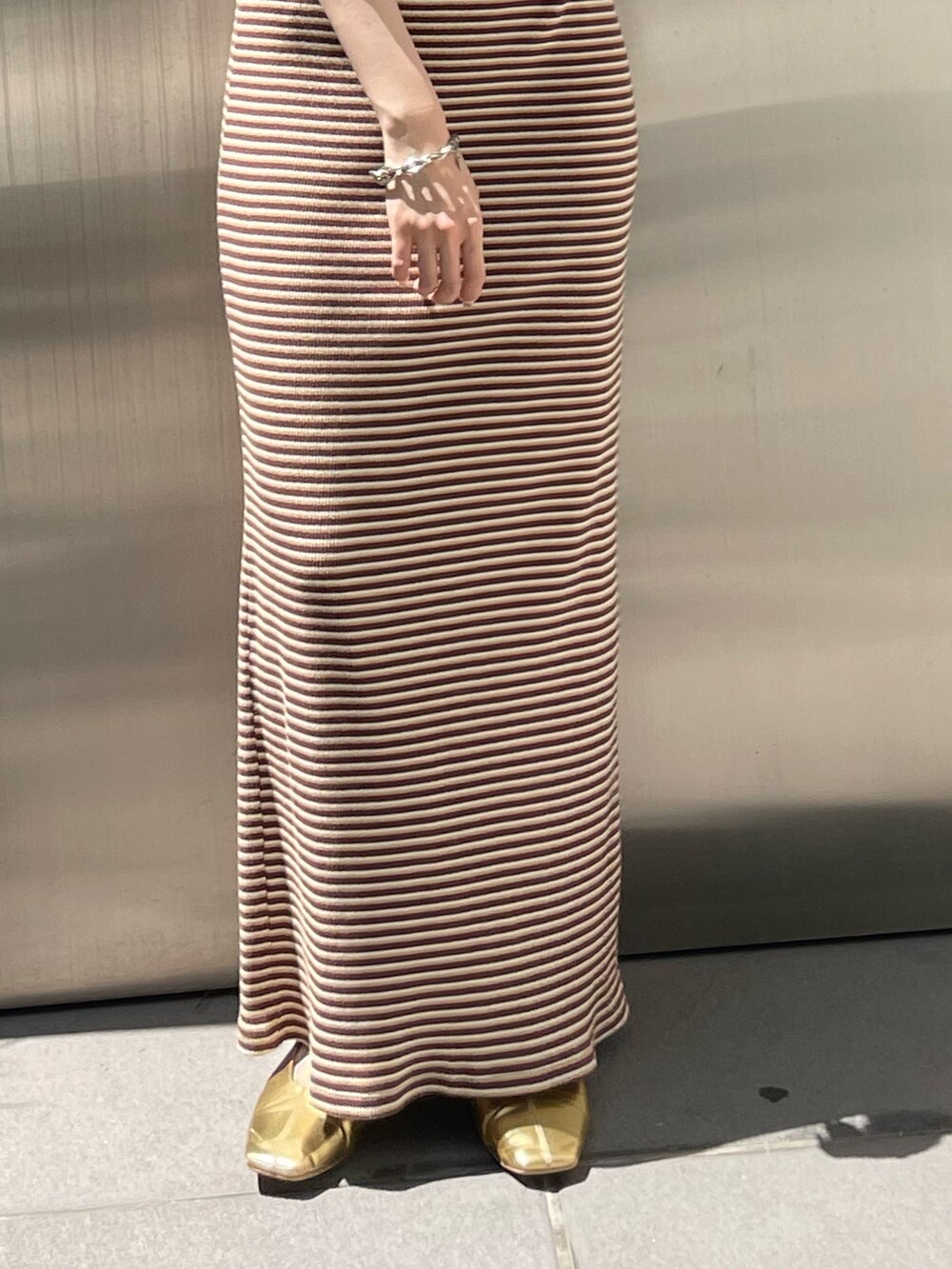 ブラウン系のワンピース、ゴールド系のパンプス、グレー系のTシャツ/カットソーを着用したレディースの夏コーディネートの6枚目の写真