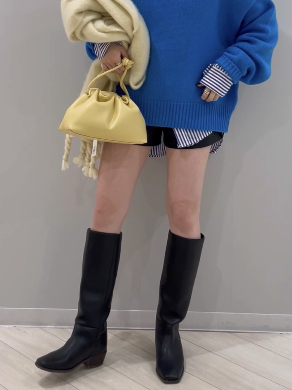 ブルー系のニット/セーター、イエロー系のクラッチバッグ、ブラック系のシューズを着用したレディースの冬コーディネートの4枚目の写真